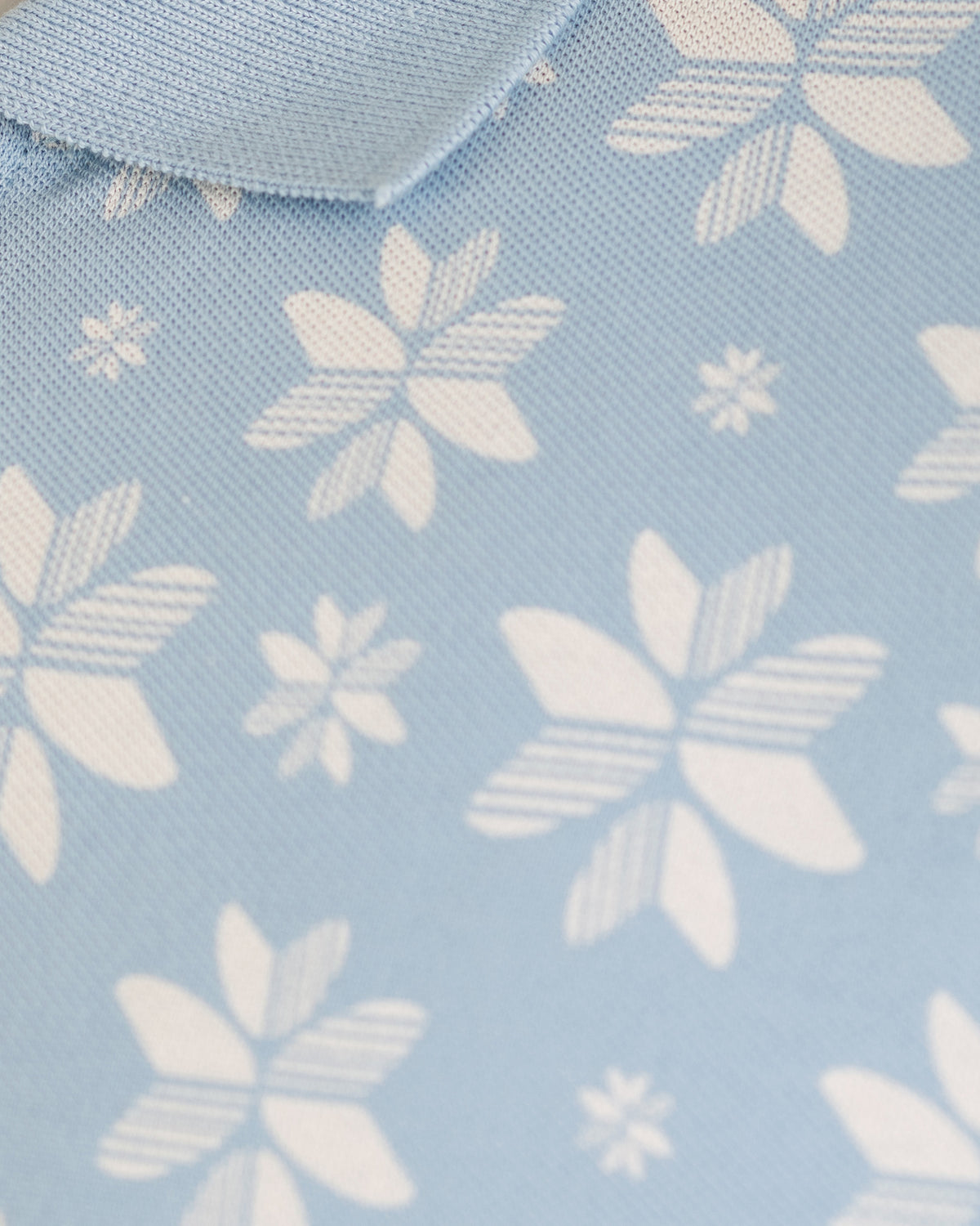 Close view of the pique knit and fish tail floral print on the Vela Polo